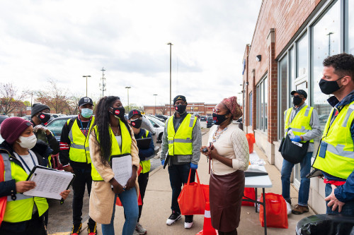 Workers in high-viz vests talking to local resident on sidewalk