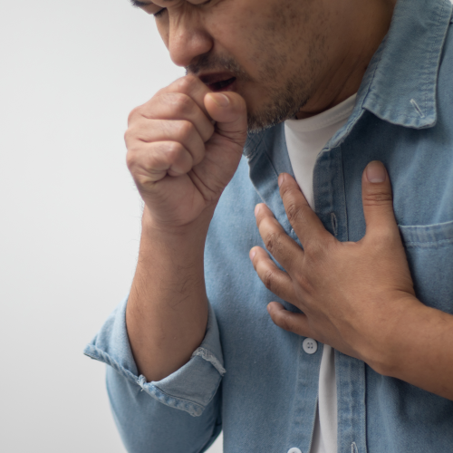 male coughing into right hand and clutching chest with left hand