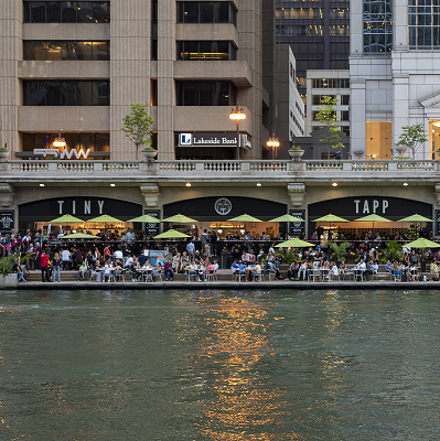 Dining tables along the River Walk with diners.