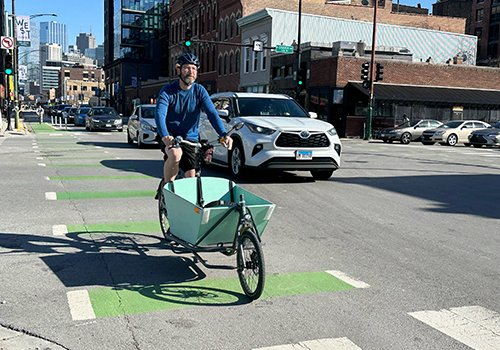 Person biking on road through intersection