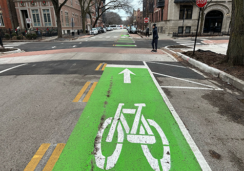 Street with green painted bike lane and bike symbol leading up to signalized intersection