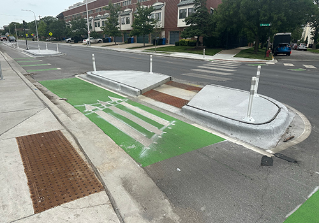 Person crossing street in crosswalk through concrete refuge island.