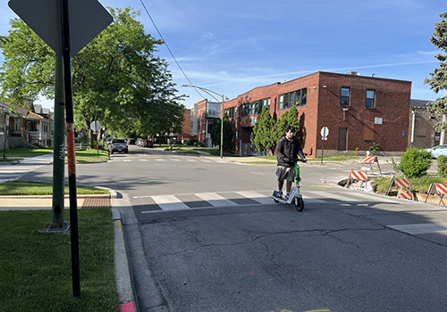 Person riding an electric stand up scooter towards camera