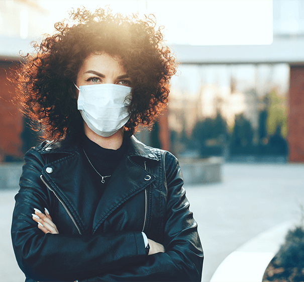 Woman with curly hair and leather jacket standing with arms crossed