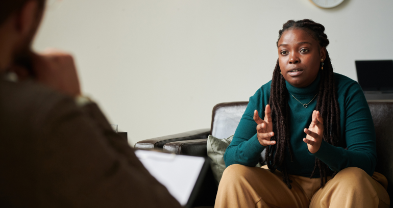 seated woman speaking with silouhetted person in foreground