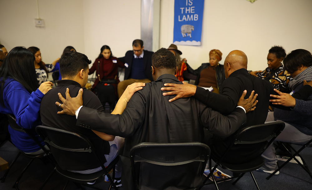 Group of people sitting in a circle with hands on each other's shoulders.